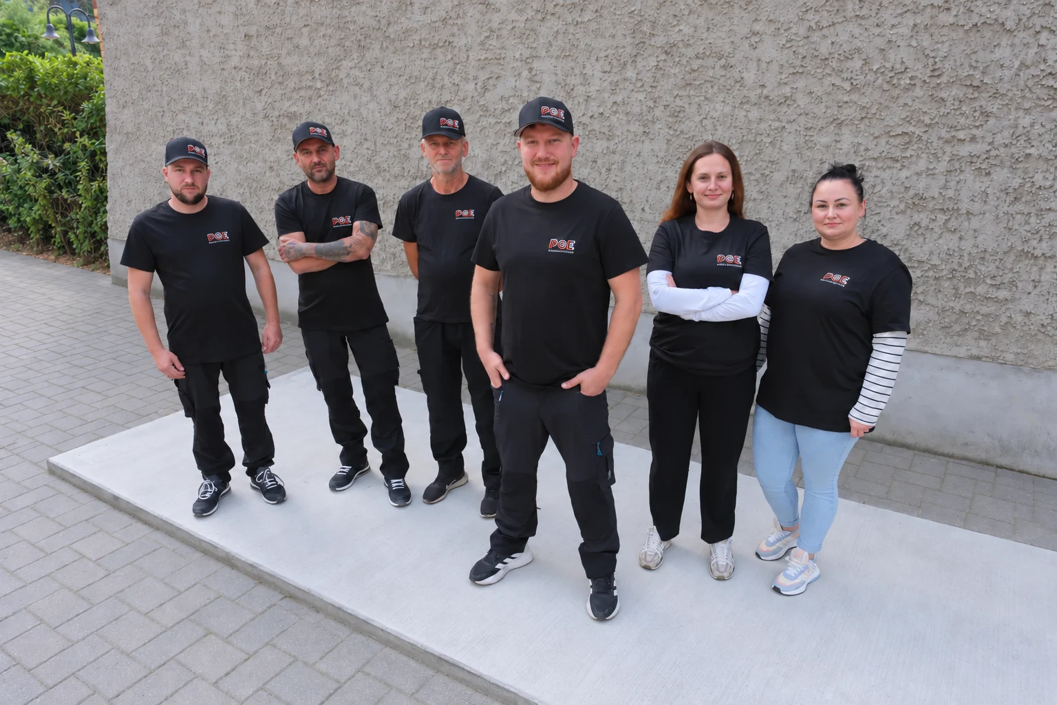 Das Team von PGE Elektrotechnik vor einer langen Berliner Hauswand